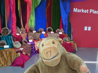 Mr Monkey looking at a colourful selection of spices and fabrics
