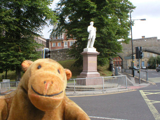 Mr Monkey looking at a statue of George Leeman