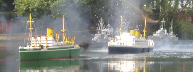 The two merchant ships under fire, with water splashing in the air