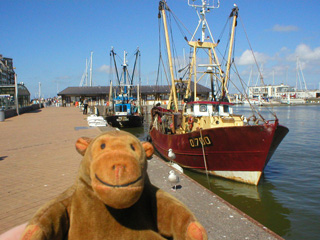 Mr Monkey looking at a trawler moored in Ostende harbour