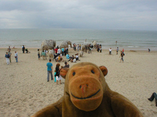 Mr Monkey walking away from the wooden elephants