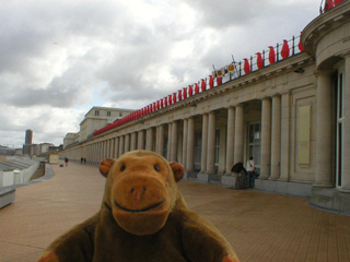 Mr Monkey looking at a row of red penguins lining the top of the Thermae Palace