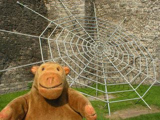 Mr Monkey looking at a metal spider web outside the Gravensteen