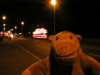 Mr Monkey watching an illuminated tram go past