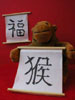 Monkey holding 'monkey' scroll, with 'good luck' scroll on wall